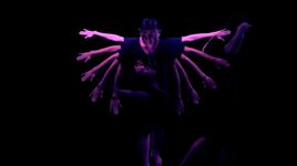 Using a mirror tool, this still uses a mirror symmetry effect on top of footage of a person dancing. They have their left hand placed over their heart and their right arm draped over their face. The setting is very dark with atmospheric blue toned lighting. A pale full moon is positioned in the center of the frame where the mirror symmetry line stands.