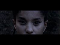 It's a shot of someone's face from the nose to forehead. They have light brown skin and their hair pulled back. They are wearing black eyeliner and in front of a blurred background.