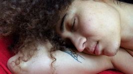 Still from the short film The Spores They Left Us (2018) by jazmín calderón torres. Closeup shot of jazmín's face as they rest on their own arm with their eyes closed, appearing to be lying down.