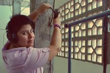 Photograph of Diana in action on a set. Diana is a transfeminist activist of indefinite gender. They turn towards the camera while wearing headphones over short black hair.