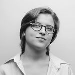 Cassidy Civiero is shown in a black and white studio portrait from the shoulders up. He has glasses and short brown hair down to his ears. Cassidy is wearing a white collared button up that is unbuttoned a little. 
