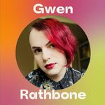Gwen Rathbone with a slight smile. Gwen has light skin, raspberry asymmetrical hair, and red lips. They wear a button-up with a sun, moon and star pattern.