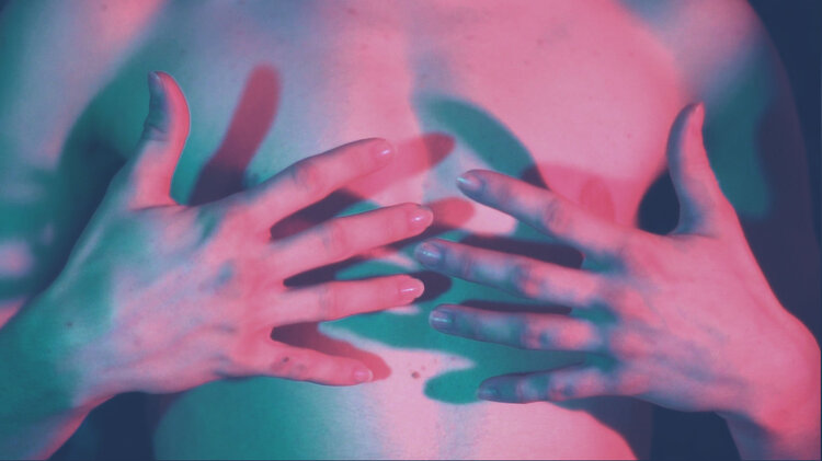 two hands over chest, pink and blue lighting
